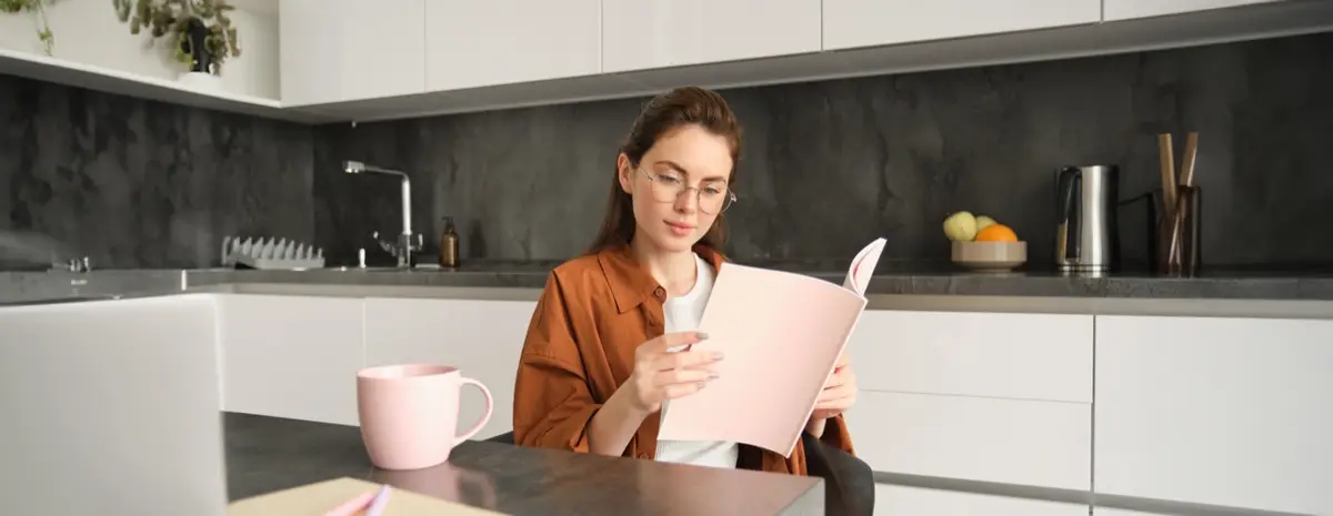 Mujer lee unos documentos en su cocina