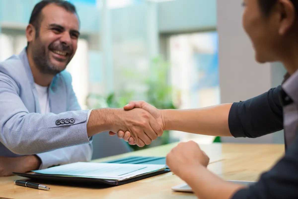 Dos personas se dan la mano sobre un escritorio